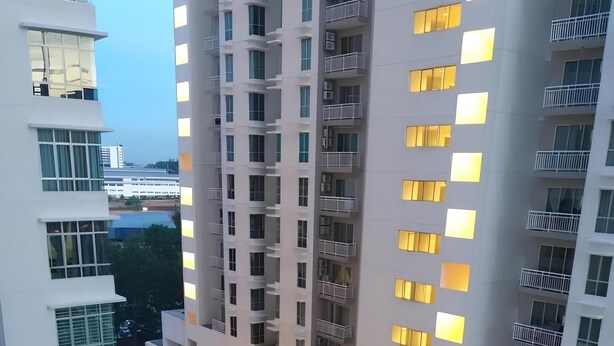 Un edificio de gran altura con varios balcones y una zona de piscina.