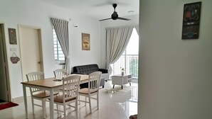 Una sala de estar moderna con comedor, muebles blancos y un balcón con cortinas.