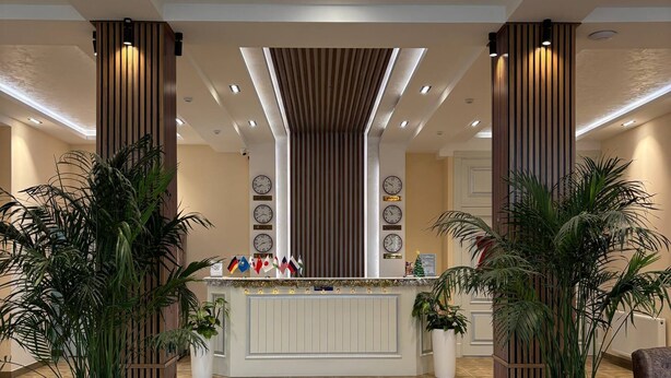 A reception area with a central counter, potted plants, and a tiled floor. - AKS HOTEL (Tashkent)
