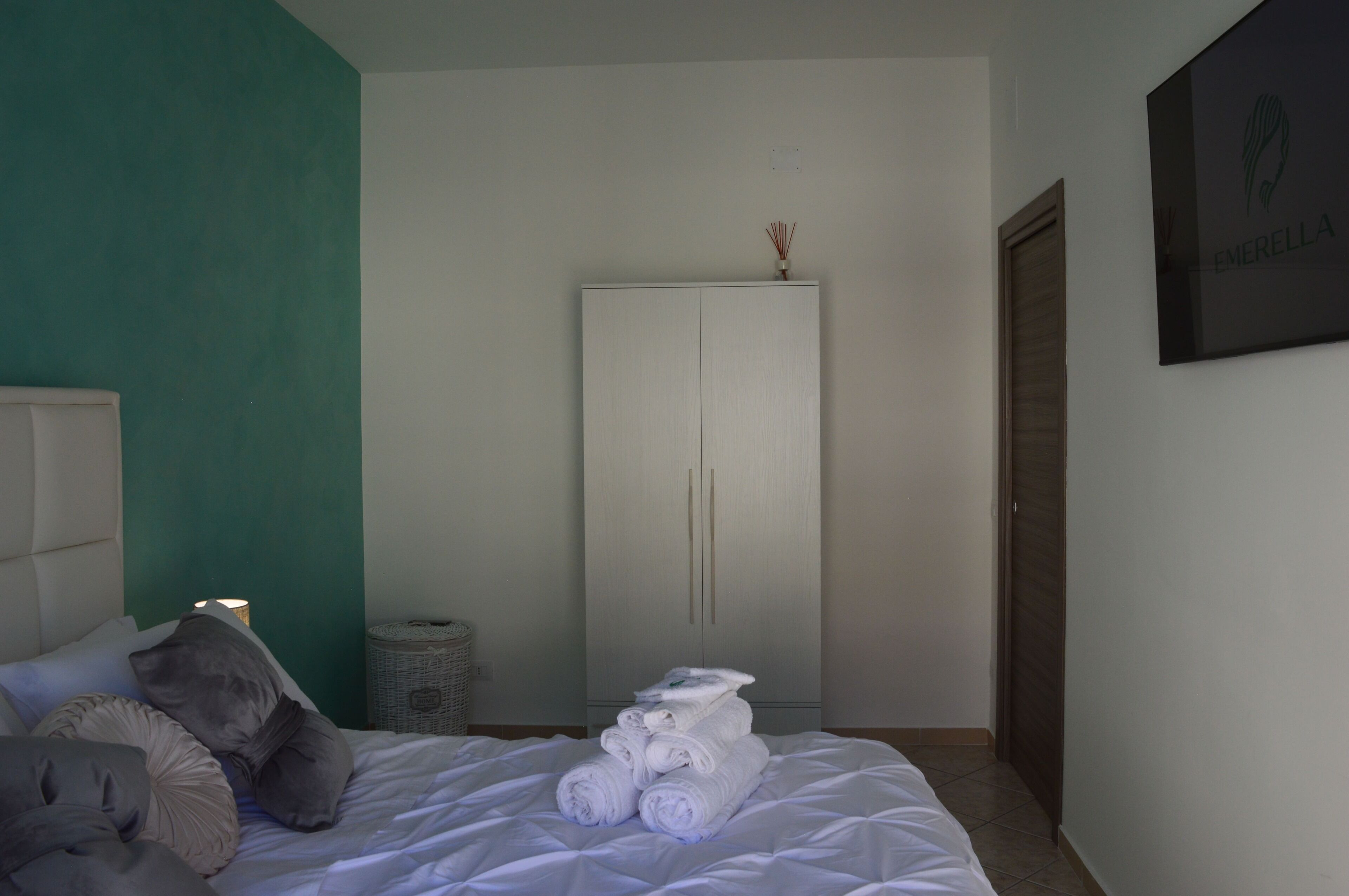 Un dormitorio con cama, almohadas, un armario y una obra de arte colgada en la pared.