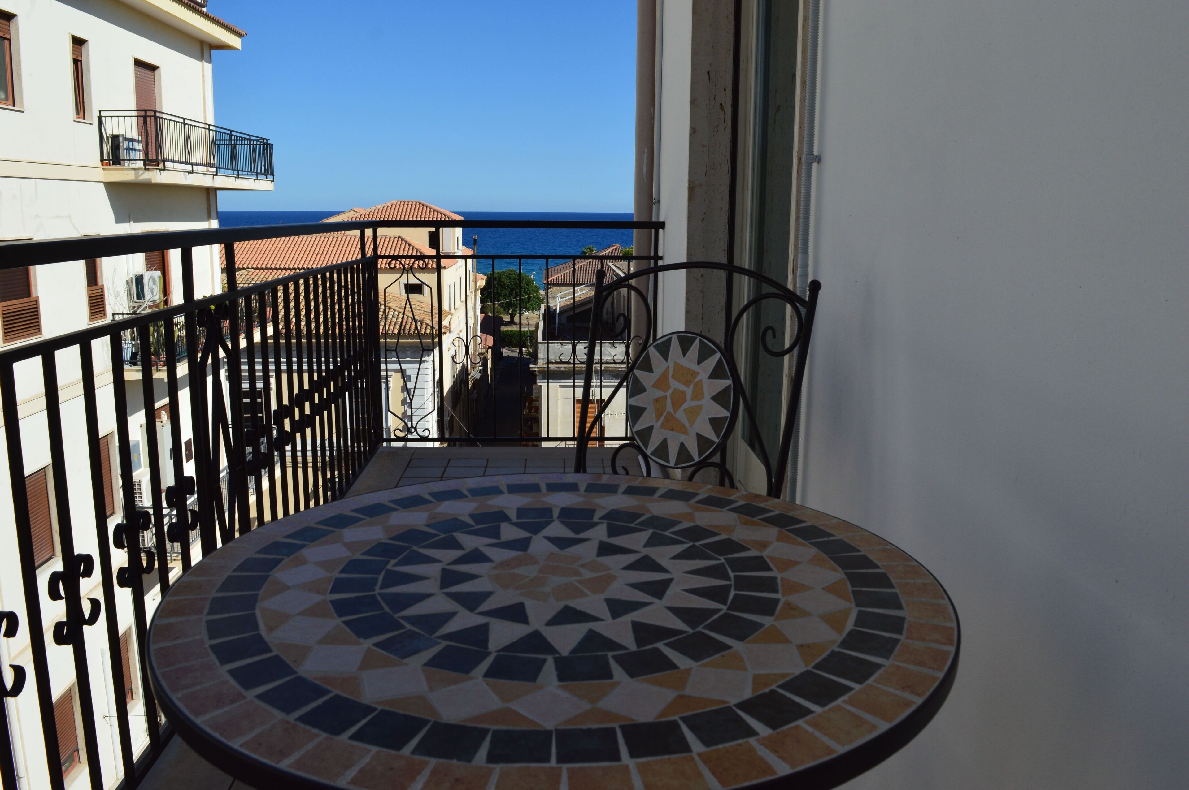 Un balcon doté d’un sol carrelé et d’une rambarde en métal.