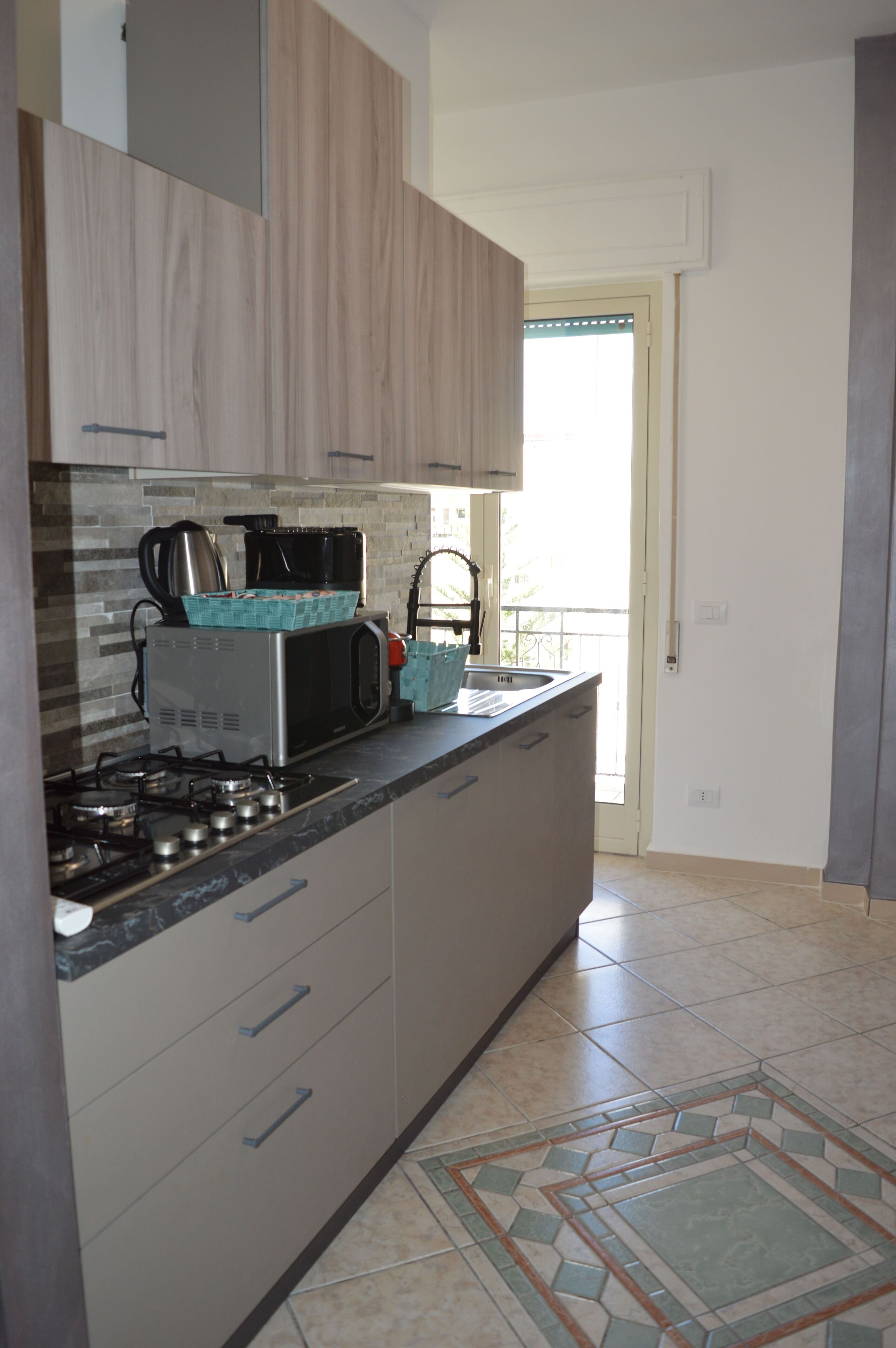 A kitchen with a stove, microwave, and coffee maker. There is a window with a view of the outside.
