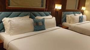 Dos camas individuales con cabeceras, ropa de cama blanca y una pared de paneles de madera.