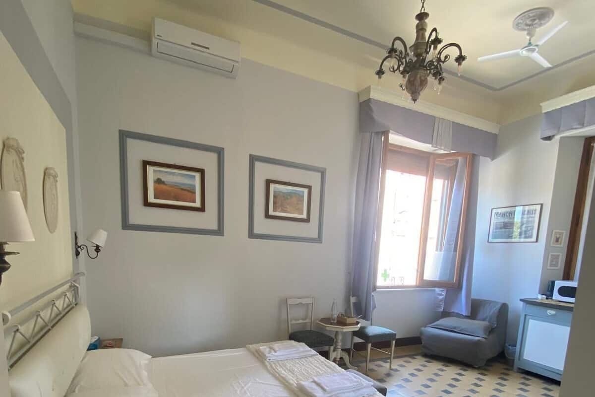 Una habitación de hotel con cama, escritorio, silla y ventana con cortinas.
