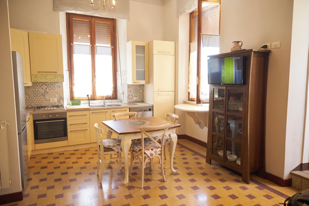 Una cocina con una mesa de comedor y sillas, un refrigerador, una estufa y armarios.