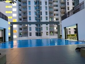 Swimmers can enjoy a refreshing dip in the rectangular pool surrounded by a tiled floor.