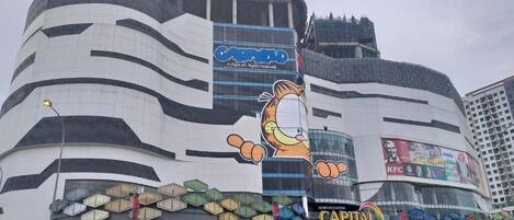 Un edificio moderno con un gran personaje de caricatura en la fachada, rodeado de varios anuncios y señalizaciones.