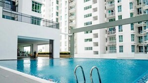 Une piscine intérieure moderne, avec une eau d’un bleu cristallin, entourée de façades blanches et de balcons.