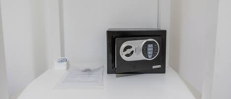 A black safe on a white pedestal with a small white object beside it.