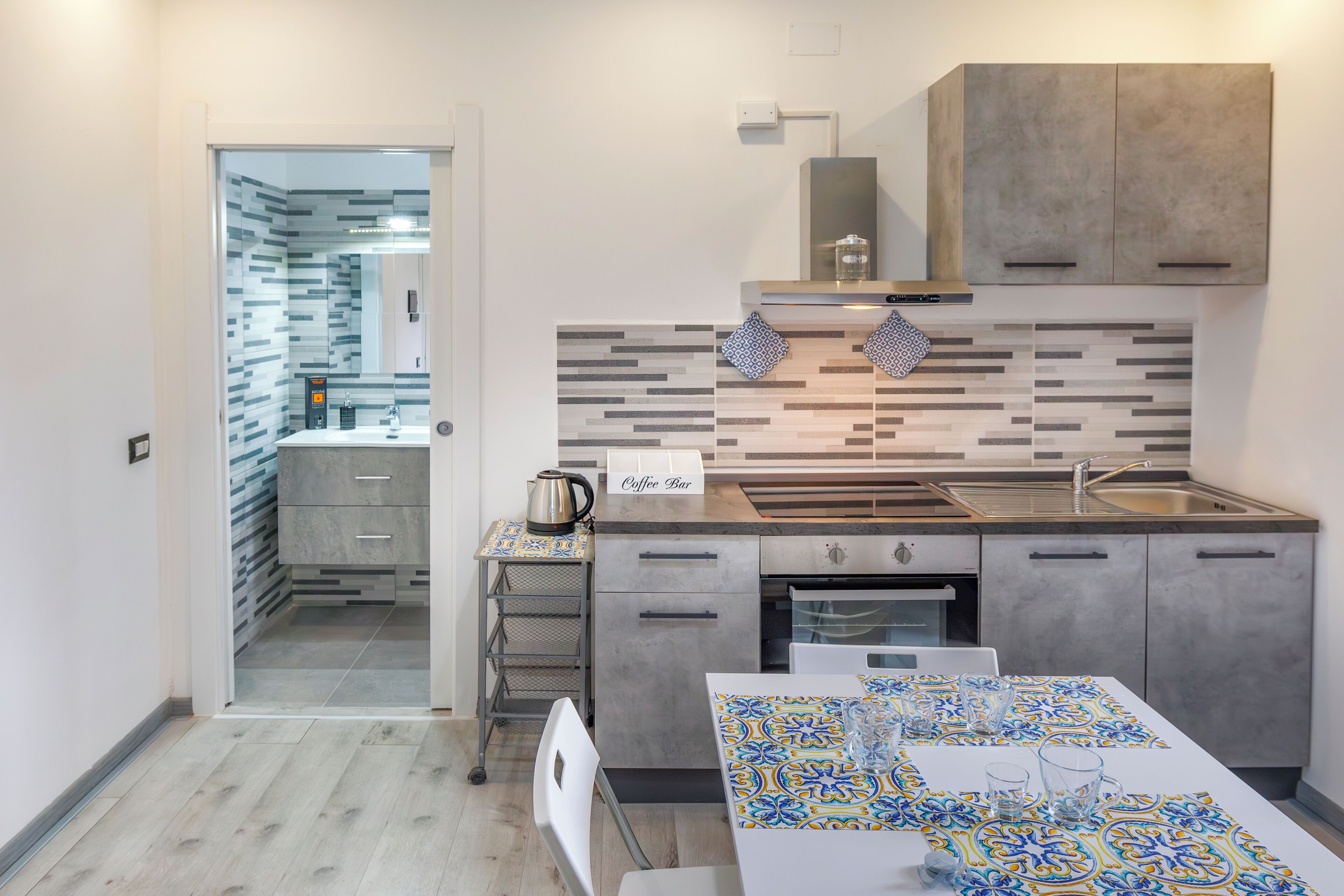 Uma cozinha moderna com um balcão de café, forno embutido e painel de azulejos.