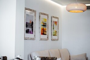 A room with a sofa, three framed pictures on the wall, and a hanging light fixture.