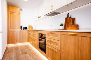 A modern kitchen with wooden cabinets, a built-in oven, and a countertop with a coffee maker and a plant.