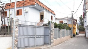 A residential street with a gated house, a yellow truck parked on the side, and a person standing near the truck. - Grand House  (Tirana)