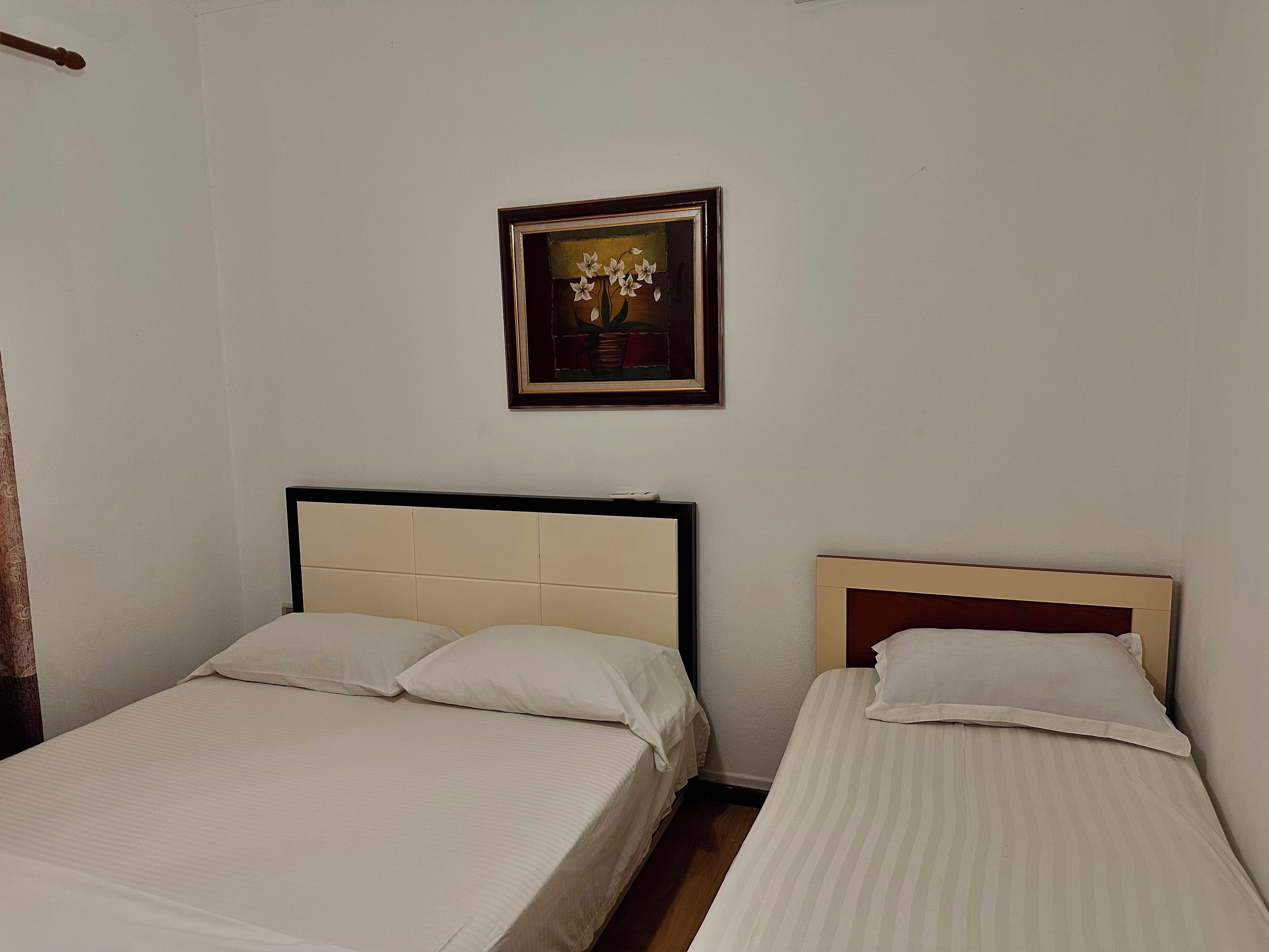 Ein Zimmer mit zwei Betten, einem gerahmten Bild an der Wand und einem Holzkopfteil.