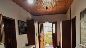 A room with wooden flooring, a bed, a bench, and a door leading outside. - Grand House  (Tirana)