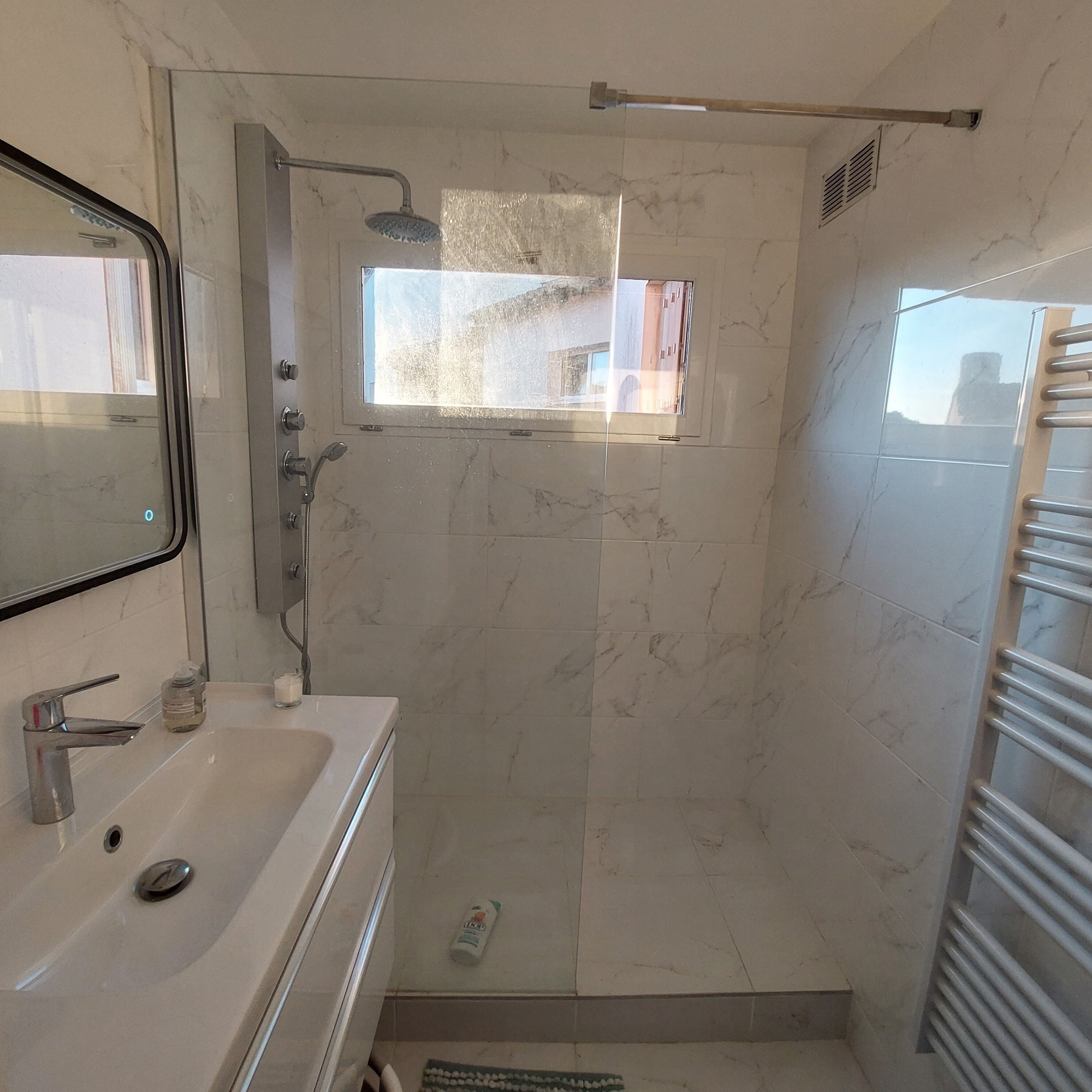 Une salle de bain avec une douche, un lavabo et un miroir.