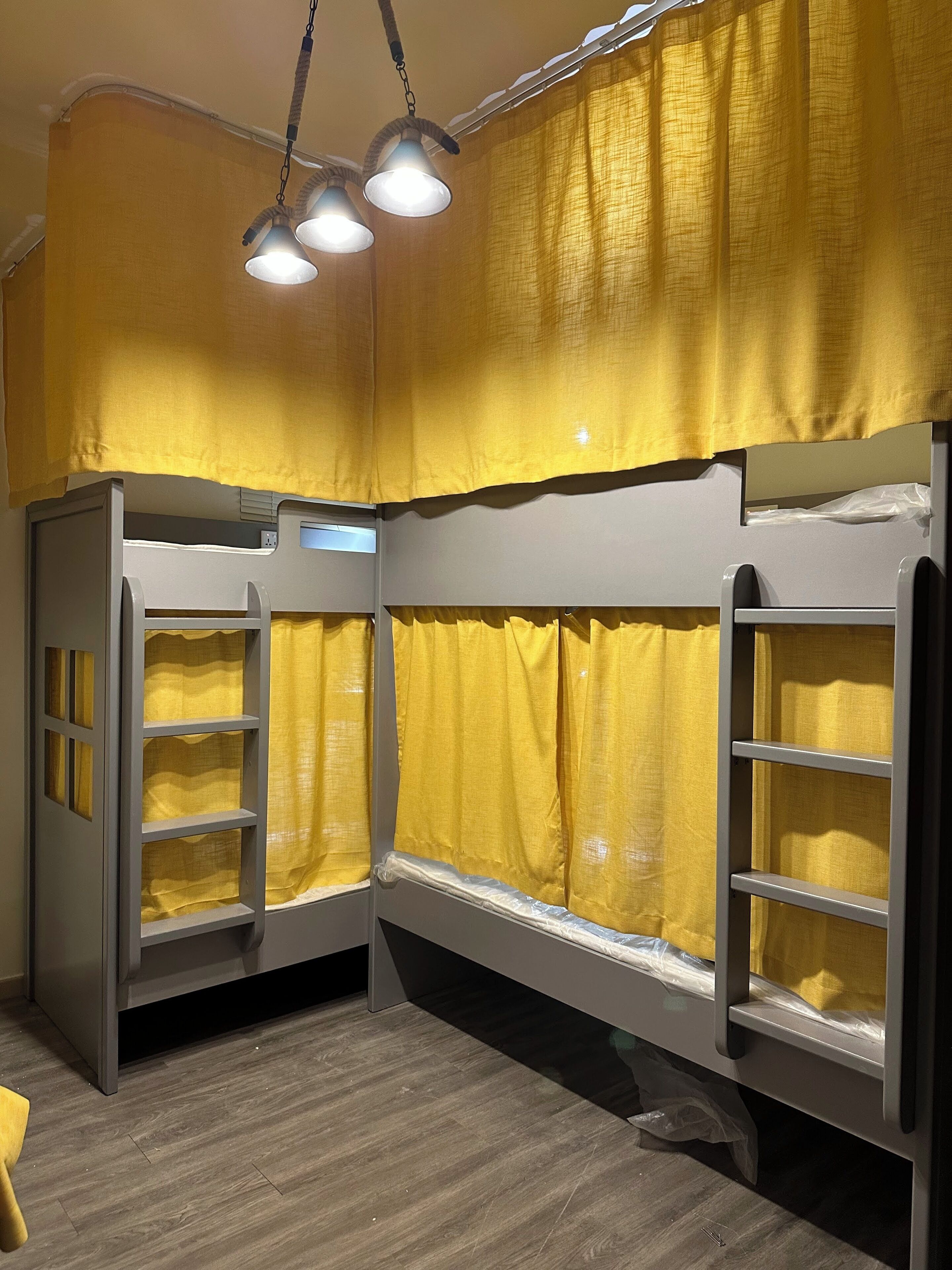 Una habitació amb llits superposats, cortines grogues i un terra de fusta.