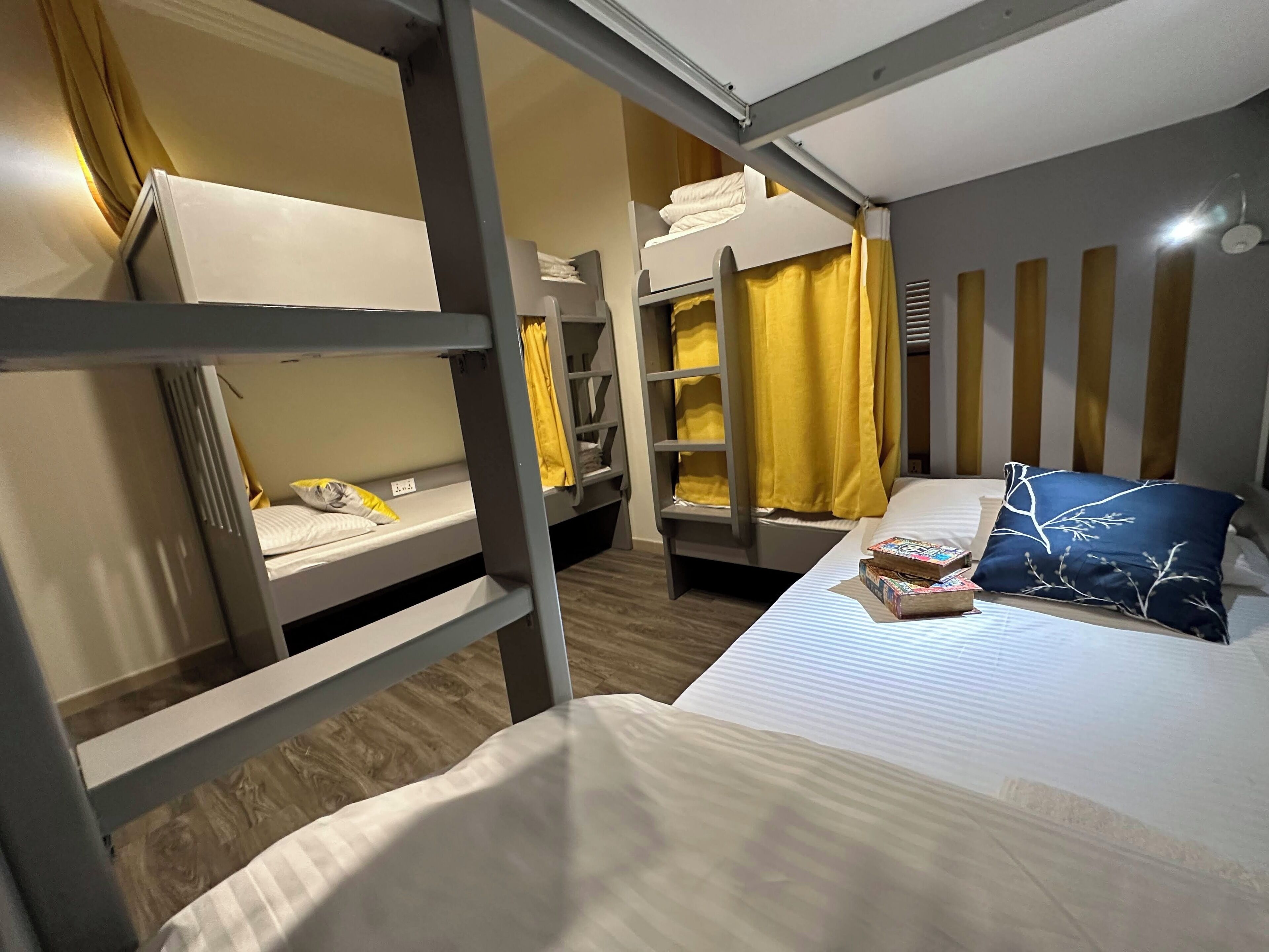 Een slaapkamer met een stapelbed, een bed met kussen, en een plank met boeken.