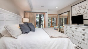 Un dormitorio con una cama grande, un aparador, un televisor y vistas al exterior.