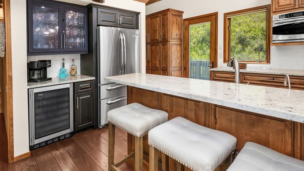 Una cocina moderna con armarios oscuros, electrodomésticos de acero inoxidable y una isla grande con taburetes de bar.
