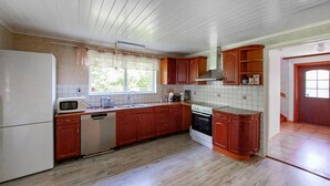 Eine Küche mit Holzausstattung, einem weißen Kühlschrank, einer Mikrowelle, einem Geschirrspüler und einem Herd.