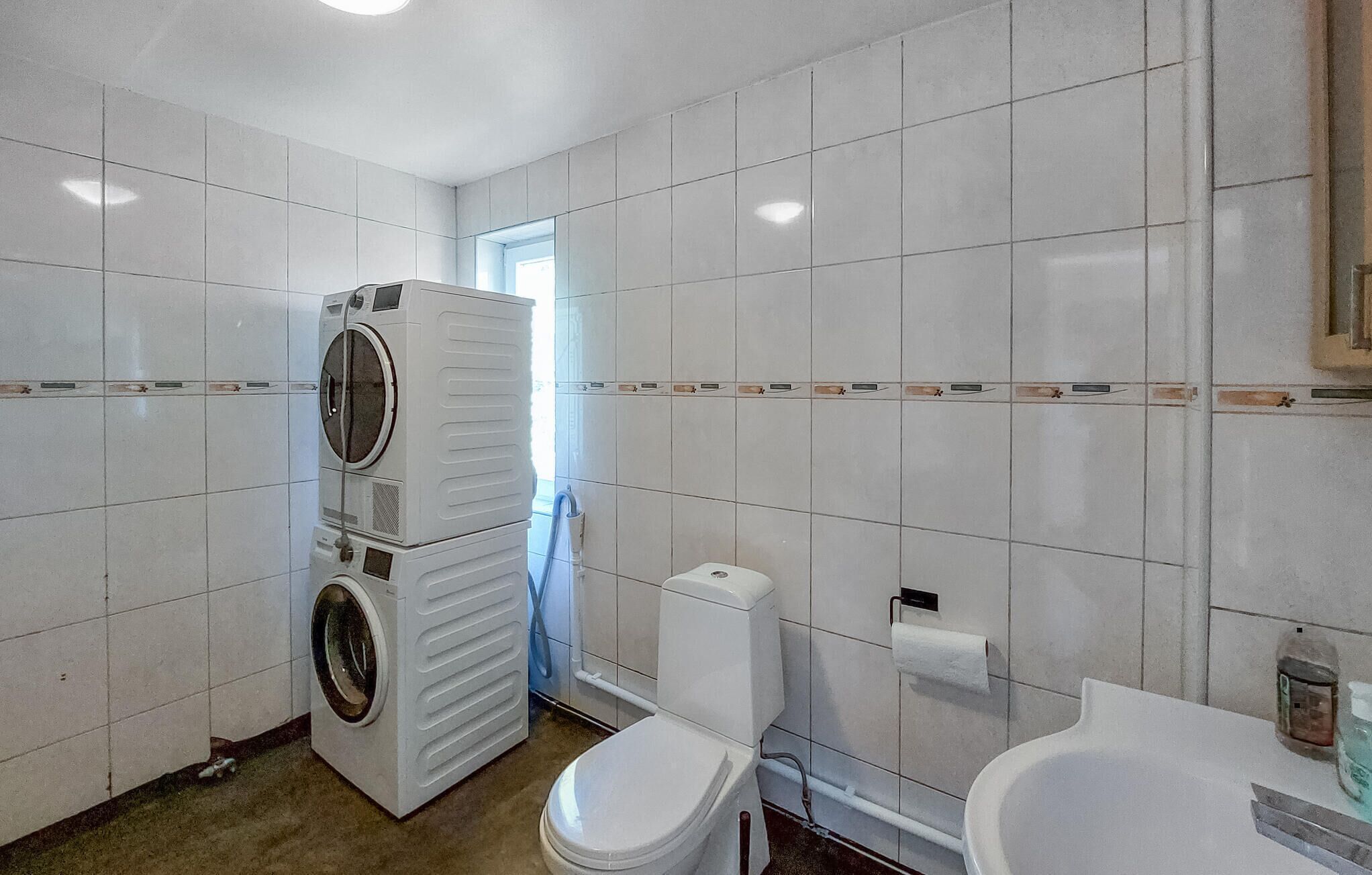 A compact bathroom with a washing machine, toilet, and sink.