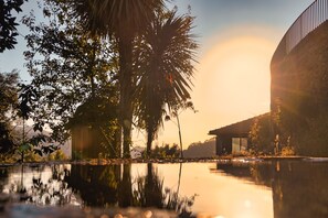 A serene lakeside view with a modern building and palm trees. - Casa S. Miguel Arcanjo - T5 (Caniçada)