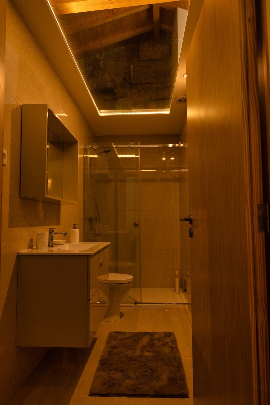Ein modernes Badezimmer mit Duschkabine aus Glas, Waschbecken mit Spiegel und Toilette.