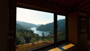 A room with a large window offering a view of a river and surrounding hills. - Casa S. Miguel Arcanjo - T5 (Caniçada)