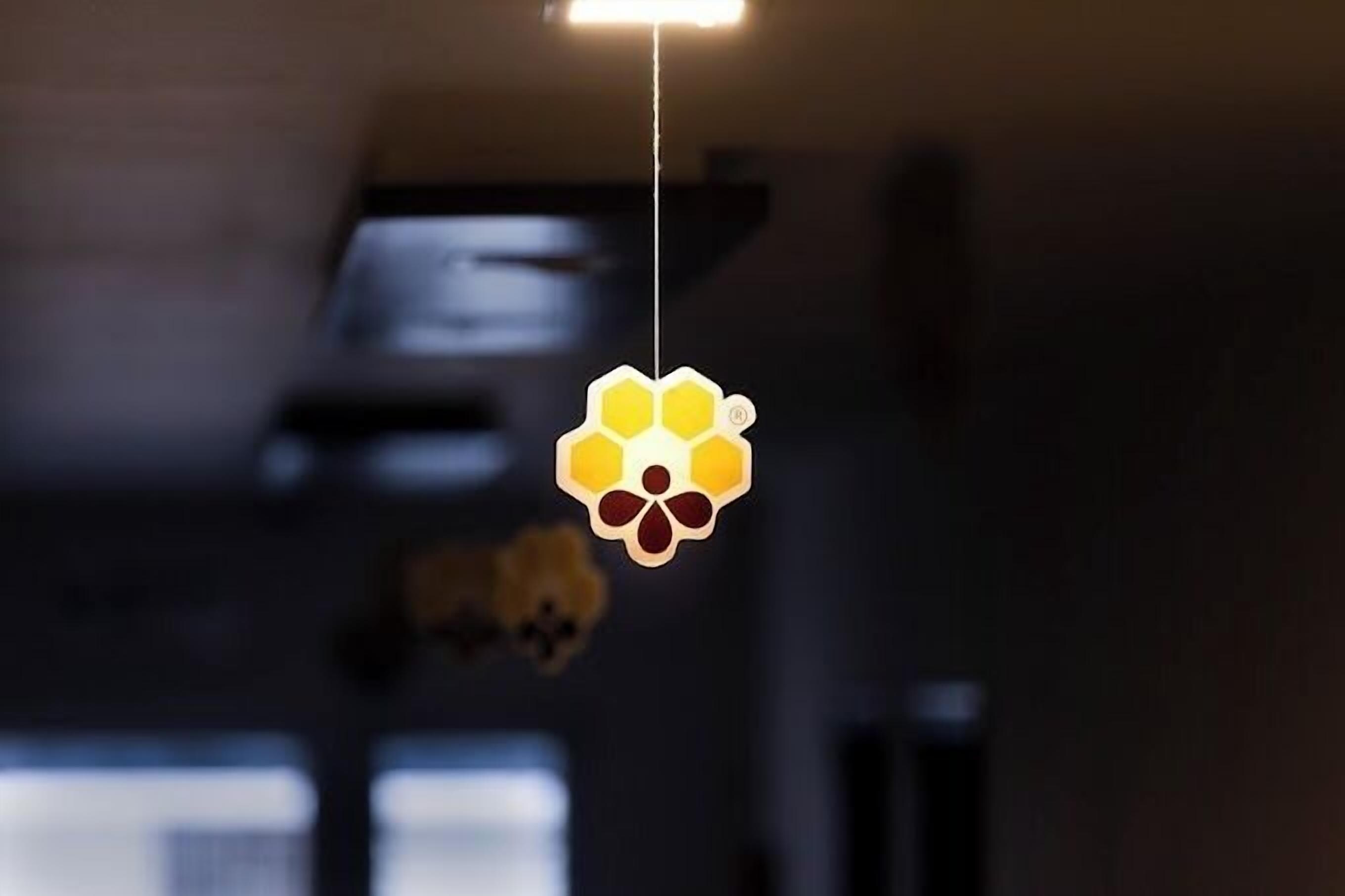 Una decoración colgante con diseño de panal y huella de pata, suspendida del techo en una habitación con poca luz.