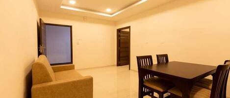 A room with a dining table, chairs, a sofa, and a ceiling fan.