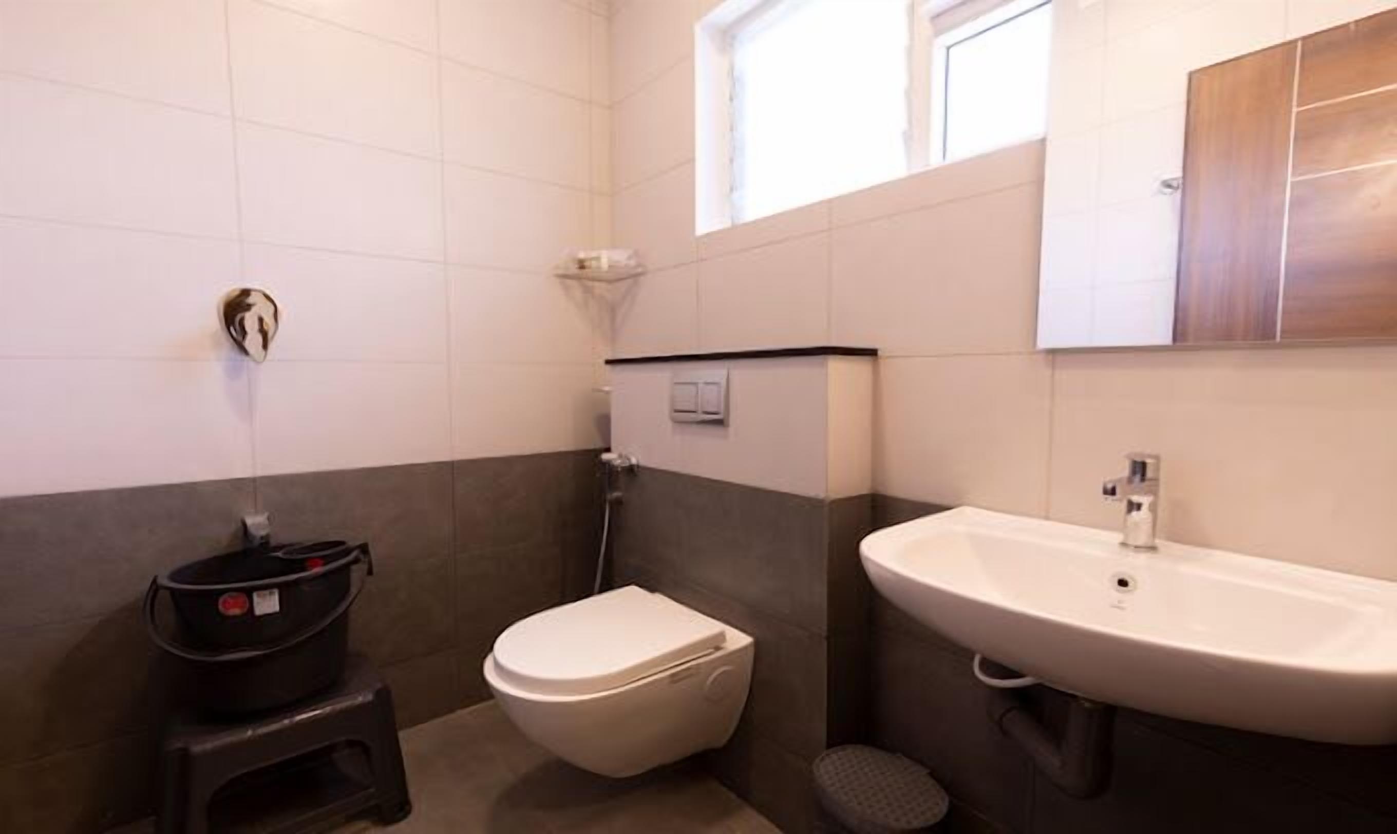 A bathroom with a toilet, sink, and a small window.