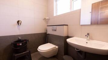 Un baño con inodoro, lavamanos y una ventana pequeña.