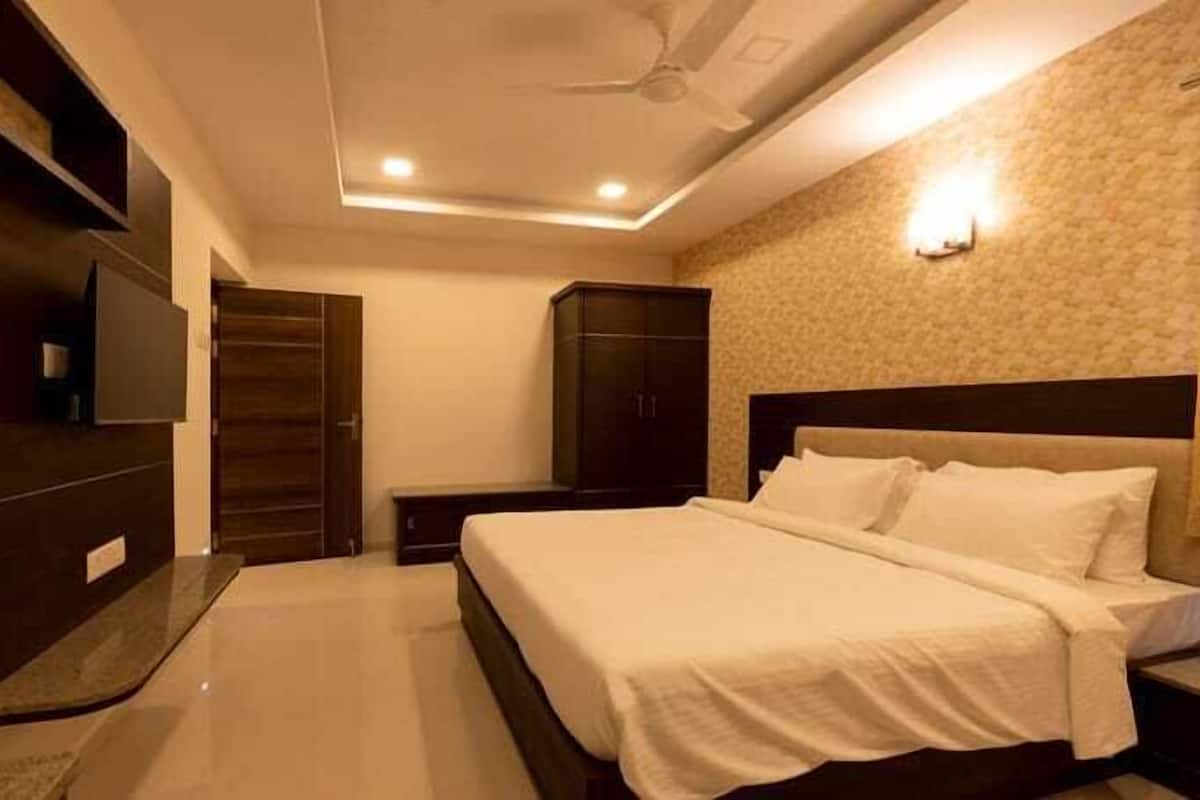 A bedroom with a bed, a wardrobe, a TV, and a ceiling fan.
