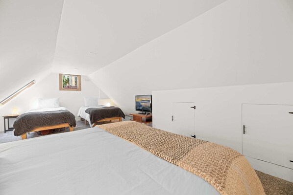 Une chambre avec un grand lit, deux petits lits, une télévision et une armoire.