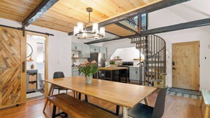 A spacious kitchen with modern appliances, a wooden dining table with benches, and a staircase leading to an upper level. - Navigate Stays Hot Tub Home 5 Min to Ski Resort (Big Bear Lake)
