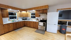 Een keuken met houten kastjes, een magnetron, een fornuis en een koelkast.