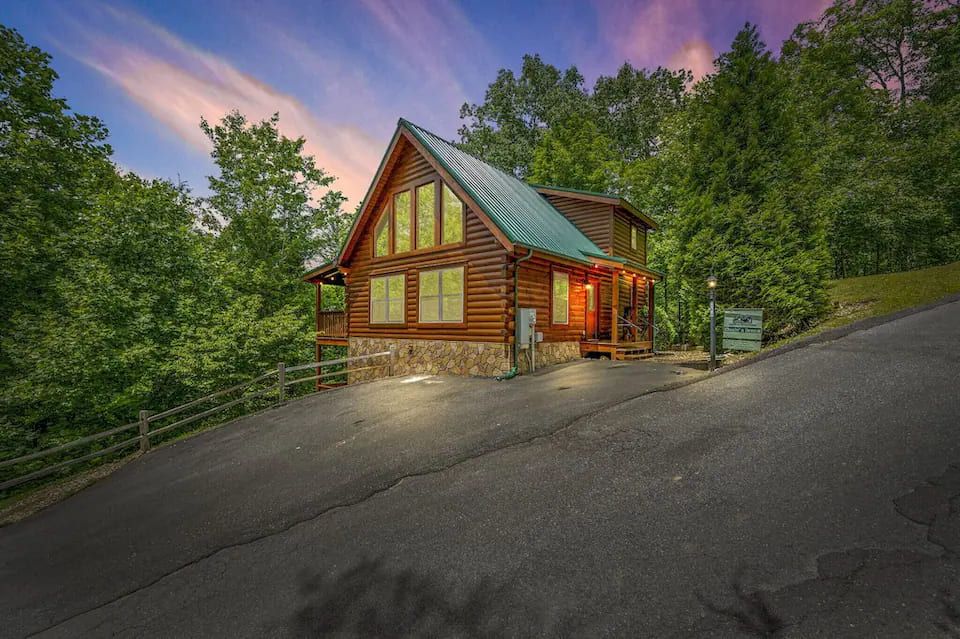 A log cabin with a metal roof, large windows, and a porch.