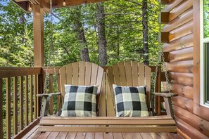 Una terraza de madera con dos sillas Adirondack y cojines a cuadros.