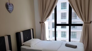 A hotel room with two beds, beige curtains, an air conditioning unit, and a view of buildings through large windows. - Paradigm Mall Platino 2BR 2FREE By Natol (Johor Bahru)