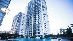 A modern high-rise building with a swimming pool in front. - Paradigm Mall Platino 2BR 2FREE By Natol (Johor Bahru)