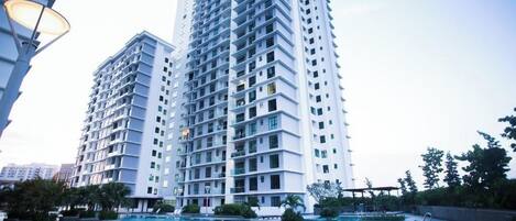 A modern high-rise building with a swimming pool in front.