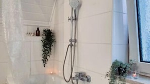 Une salle de bain moderne avec une baignoire sur pieds, une douche et une fenêtre.