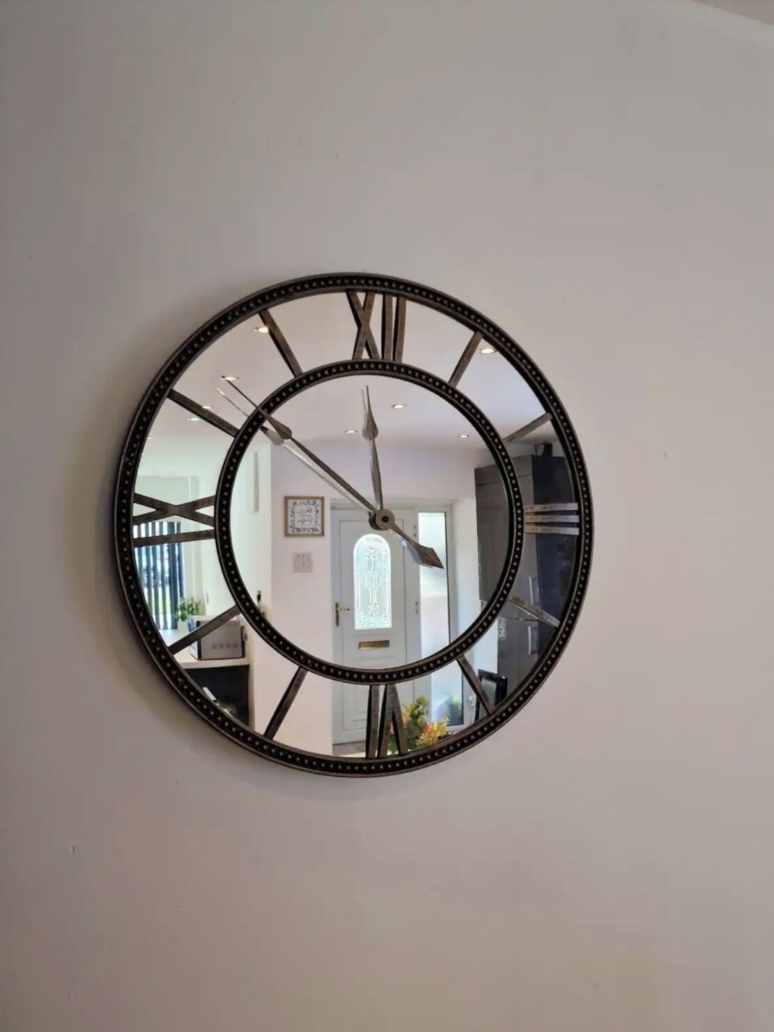 A round wall clock with Roman numerals and a decorative frame.