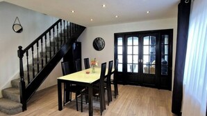A dining area with a wooden floor, a staircase, and a black-framed window. - Charming 3 Bedroom House in Sheffield (Sheffield)