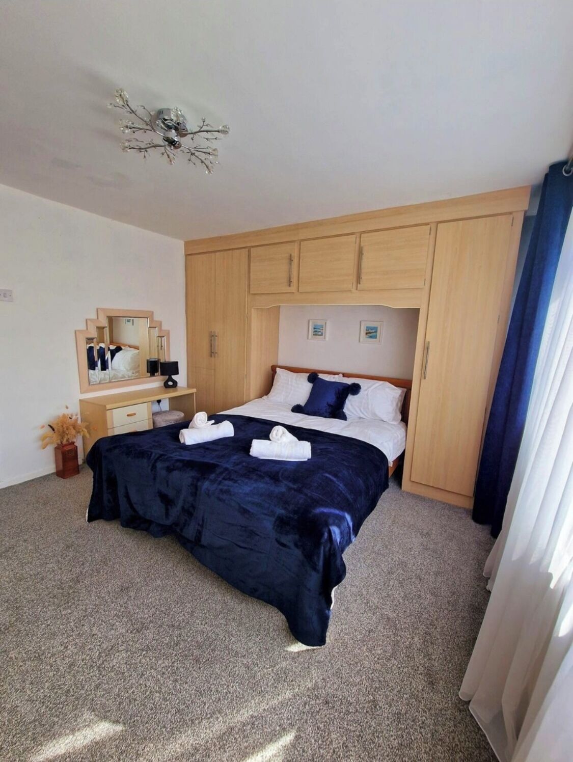 A bedroom with a bed, a dresser, a mirror, and a ceiling light fixture.