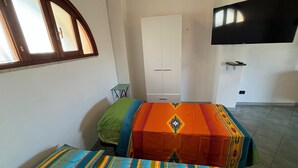 A bedroom with a bed, a wardrobe, a small table, and a TV mounted on the wall. - Vacation home with beautiful sea view near Guidaloca, Scopello and the Zingaro (Castellammare del Golfo)