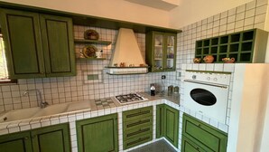 A kitchen with green cabinets, a white stove, and a tiled backsplash. - Vacation home with beautiful sea view near Guidaloca, Scopello and the Zingaro (Castellammare del Golfo)