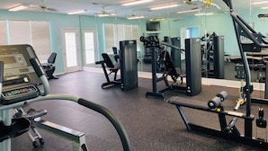 Ein Fitnessstudio mit verschiedenen Trainingsgeräten, darunter Laufbänder, Kraftgeräte und Kurzhanteln.