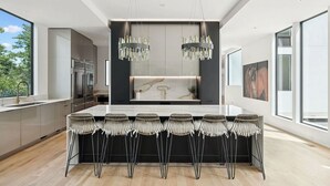 Una cocina moderna con una isla central, electrodomésticos de acero inoxidable y un amplio ventanal que proporciona luz natural.